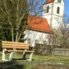 Ergonomische Sitzbank mit Lärchenholzlatten und Füßen aus Beton steht an einem öffentlichen Weg