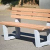 Ergonomische Sitzbank mit Lärchenholzlatten und Füßen aus Beton steht an einem öffentlichen Weg