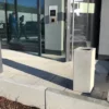 Ascher Kubus steht vor einem modernen Firmengebäude mit großer Glasfront