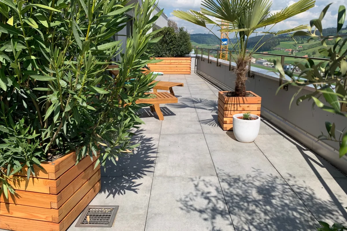 Verschieden große Pflanzkästen aus Holz stehen bepflanzt auf einer privaten Terrasse
