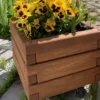 Kleiner Pflanzkübel aus Holz, bepflanzt mit gelben Blumen in einem privaten Garten