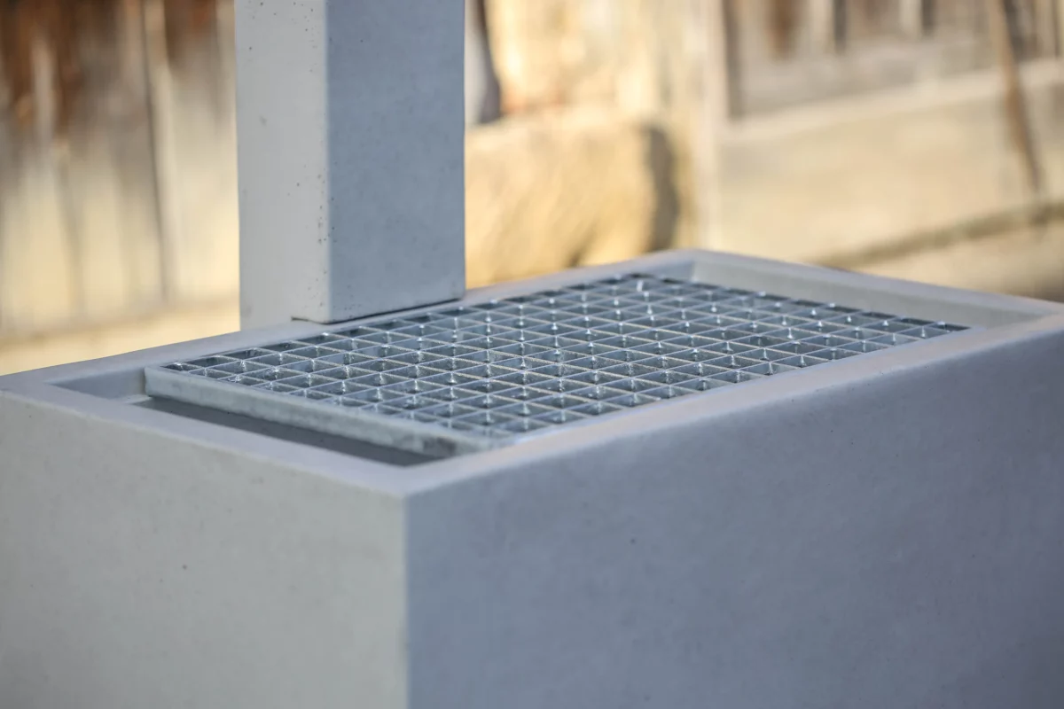 Zapfbrunnen aus Sichtbeton steht auf einem öffentlichen Gelände