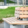 Rundbank mit Lärchenholzlatten, Rückenlehne und Betonfüßen steht auf einem öffentlichen Platz.