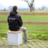 Hocker aus Beton mit Sitzauflage aus Lärchenholz steht auf öffentlicher Grünanlage