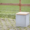Hocker aus Beton mit Sitzauflage aus Lärchenholz steht auf öffentlicher Grünanlage