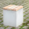 Hocker aus Beton mit Sitzauflage aus Lärchenholz steht auf öffentlicher Grünanlage