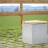 Hocker aus Beton mit Sitzauflage aus Lärchenholz steht auf öffentlicher Grünanlage