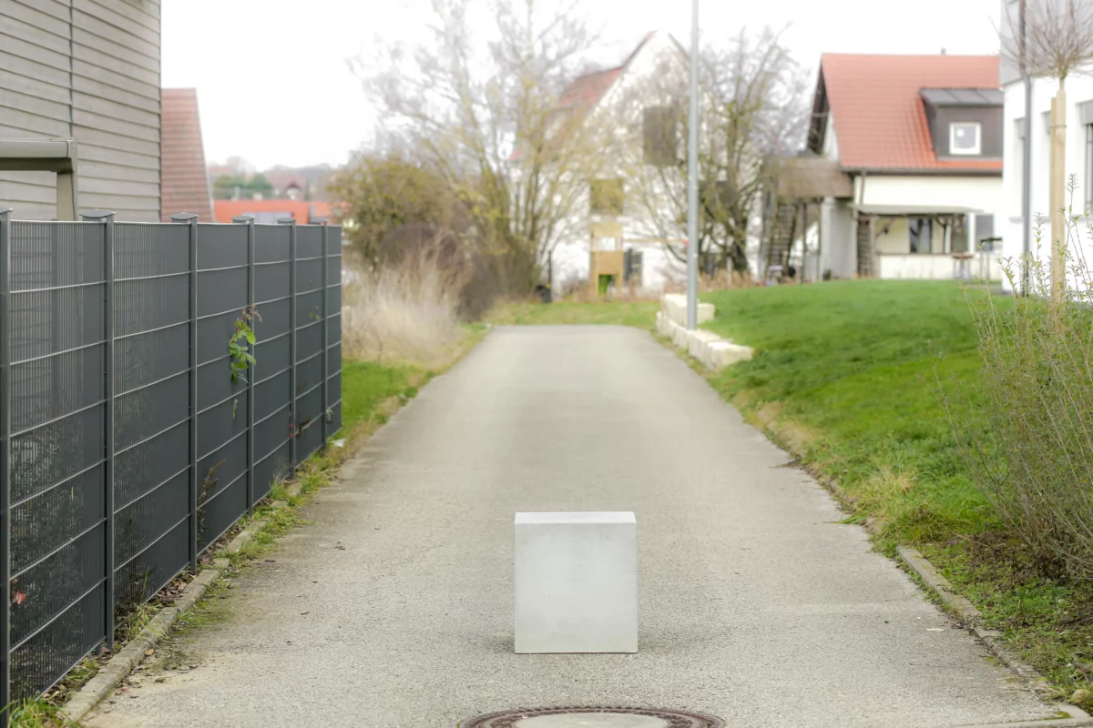Massiver Poller aus Sichtbeton steht auf öffentlichem Weg zur Durchfahrtsbeschränkung