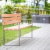 Bank aus Metall und Lärchenholz steht vor einem öffentlichen Gebäude
