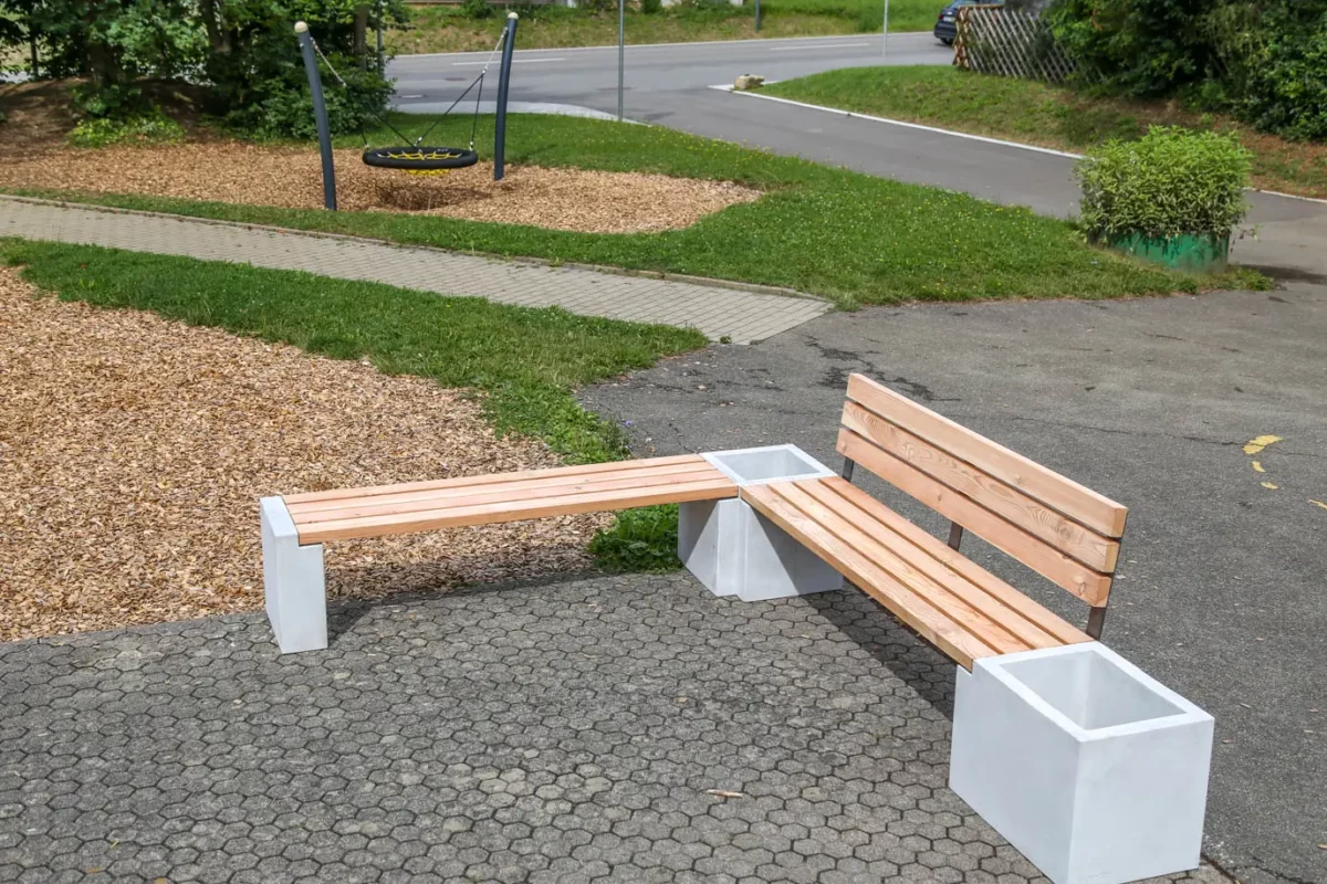 Eckbank aus Beton und Lärchenholz steht auf öffentlichem Platz