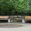 Armlehne feuerverzinkt mit Lärchenholzauflage zum optionalen Aufschrauben auf Outdoor-Sitzbank steht in einem öffentlichen Bereich