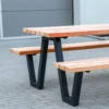 Moderne Sitzgruppe aus schwarzem Gestell und Holzauflagen steht auf öffentlichem Grund