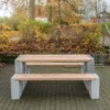Sitzgruppe aus Sichtbeton und Lärchenholz steht in einem öffentlichen Park