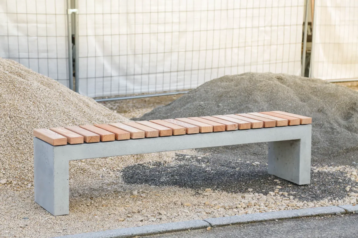 Massive Sitzbank aus Sichtbeton, optional mit Sitzauflage aus Holzdielen, steht in öffentlichem Bereich