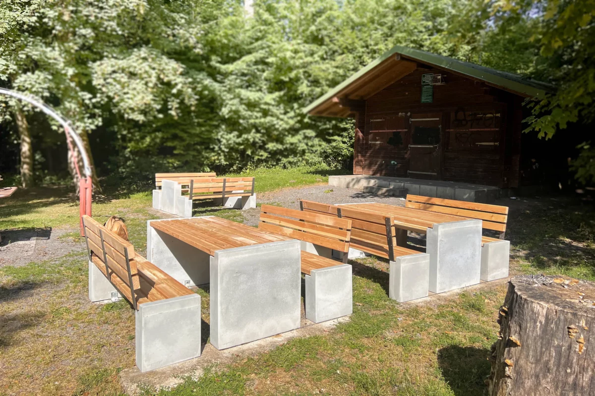Sitzgruppe aus Sichtbeton und Lärchenholz steht in einem öffentlichen Park