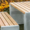 Sitzgruppe aus Sichtbeton und Lärchenholz steht in einem öffentlichen Park