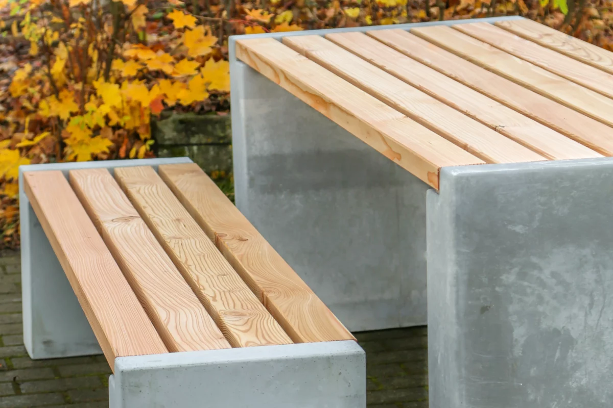 Sitzgruppe aus Sichtbeton und Lärchenholz steht in einem öffentlichen Park
