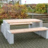 Sitzgruppe aus Sichtbeton und Lärchenholz steht in einem öffentlichen Park
