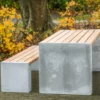 Sitzgruppe aus Sichtbeton und Lärchenholz steht in einem öffentlichen Park