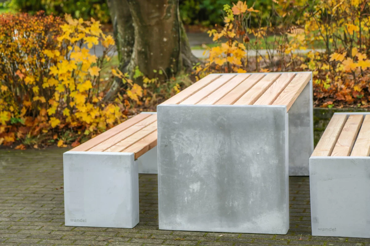 Sitzgruppe aus Sichtbeton und Lärchenholz steht in einem öffentlichen Park