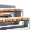 Tisch für Außenbereich mit abgerundeten Standfüßen aus Beton und längs verlaufenden Holzdielen steht auf öffentlichem Grund