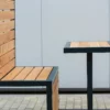 Moderne Sitzgruppe aus schwarzem Gestell und Lärchenholz steht in einem öffentlichen Bereich