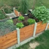 Bepflanztes Hochbeet über Ecke aus Lärchenholz und Beton steht in einem privaten Garten mit viel Grün