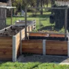 Hochbeet über Ecke aus Lärchenholz und Beton steht in einem privaten Garten mit viel Grün