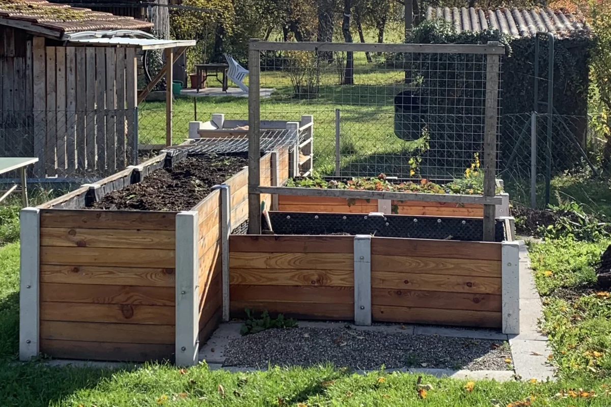 Hochbeet über Ecke aus Lärchenholz und Beton steht in einem privaten Garten mit viel Grün