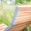 Liegebank aus Metall und Holz steht im Außenbereich vor einer grünen Wiese