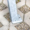 Liegebank aus Metall und Holz steht im Außenbereich vor einer grünen Wiese